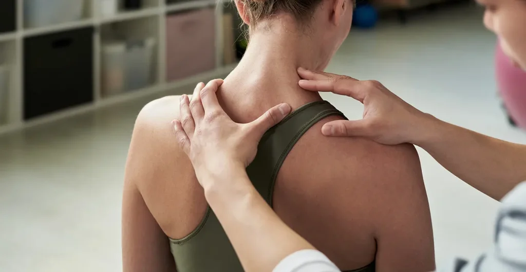 A chiropractor assessing a female patient's neck and upper back during an evaluation for pain relief.