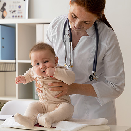 A pediatric chiropractor gently supporting an infant during a wellness exam in a clinic.